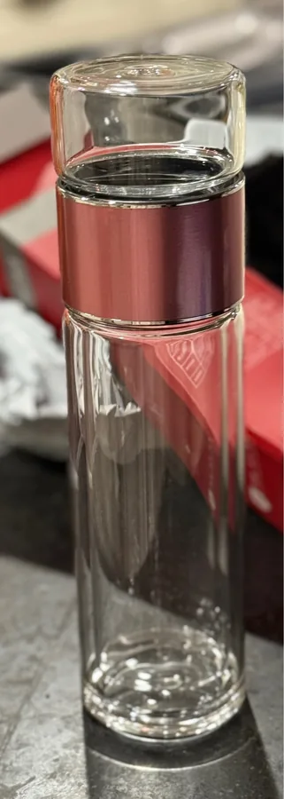 The double-wall glass tea bottle with a rose gold collar standing on a table. Photographed by U***r, a verified buyer